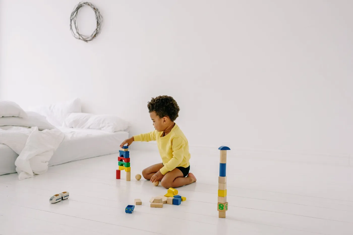 A child playing calmly with wooden blocks on the floor at home.
